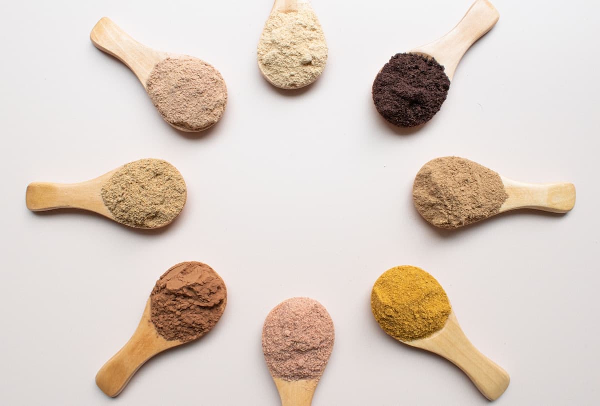 Ayurvedic herbs and spice powders arranged in wooden spoons