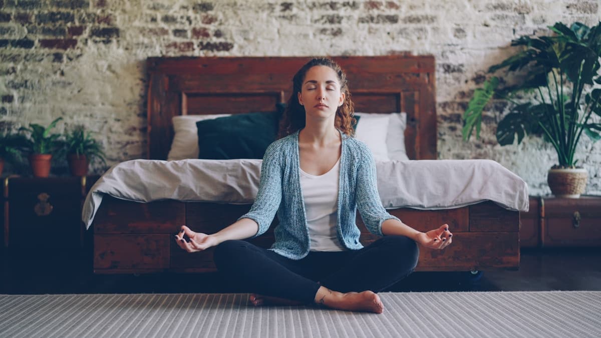 Woman meditating peacefully in a sunlit bedroom